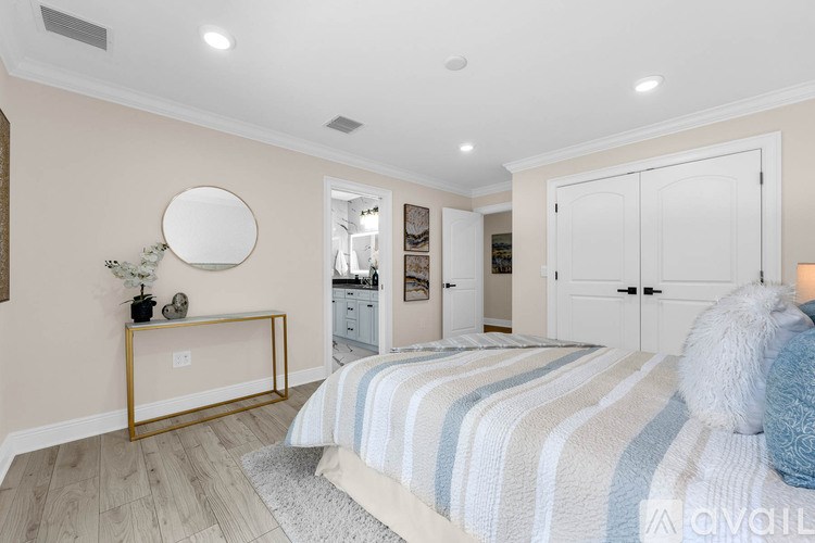 A bedroom with a bed, a mirror, and a lamp.