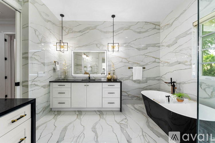 A bathroom with a marble patterned wall and a black and white bathtub.