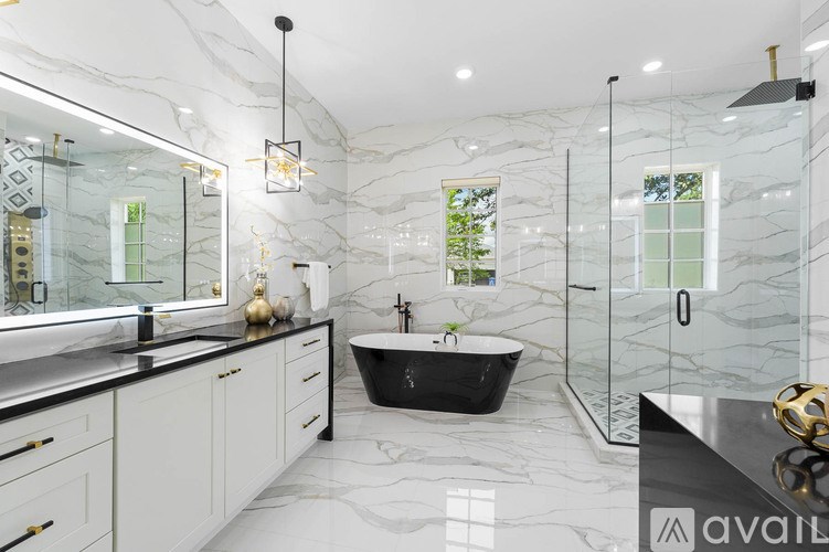 A bathroom with a black claw foot tub and marble floors and walls.