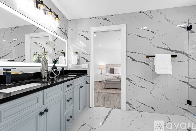 A bathroom with marble walls and a vanity with a sink and mirror.