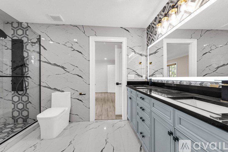 A bathroom with marble floors and walls, a white toilet, and a vanity with a mirror.