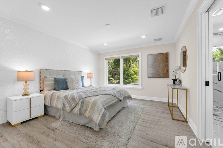 A bedroom with a large bed and a window overlooking greenery.
