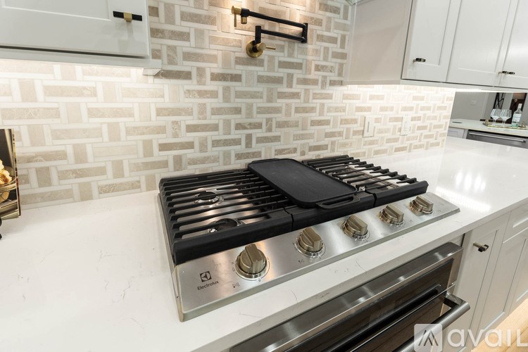 A modern kitchen with a white tiled backsplash and a stainless steel stove top.