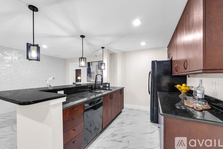 A modern kitchen with dark wood cabinets and black countertops.