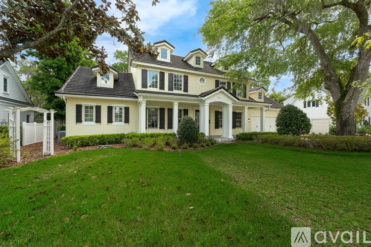 A large, two-story house with a white exterior and a black roof.