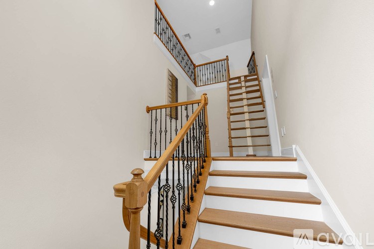 A staircase with wooden steps and a black wrought iron railing.