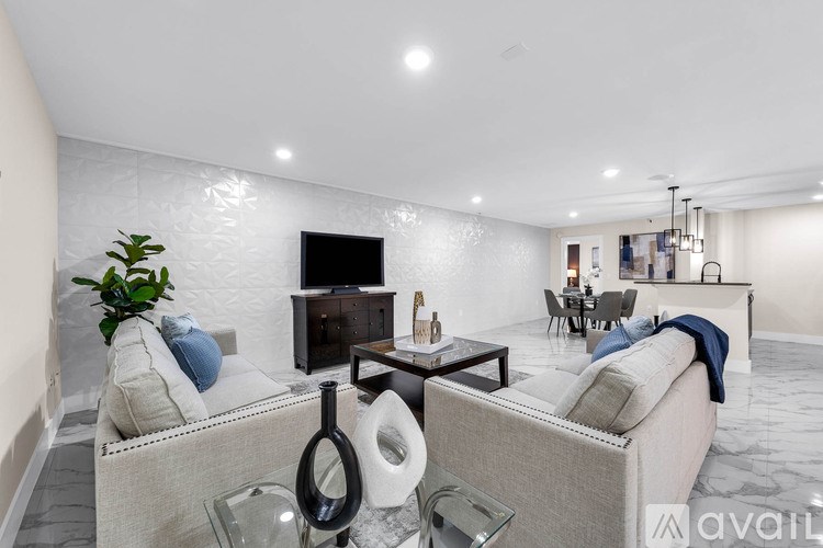 A modern living room with a grey sofa, a glass coffee table, and a TV on the wall.