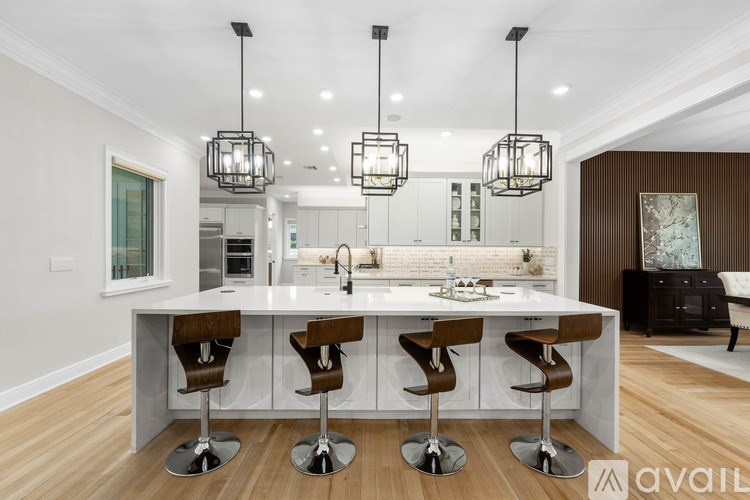A modern kitchen with a white island and brown bar stools.