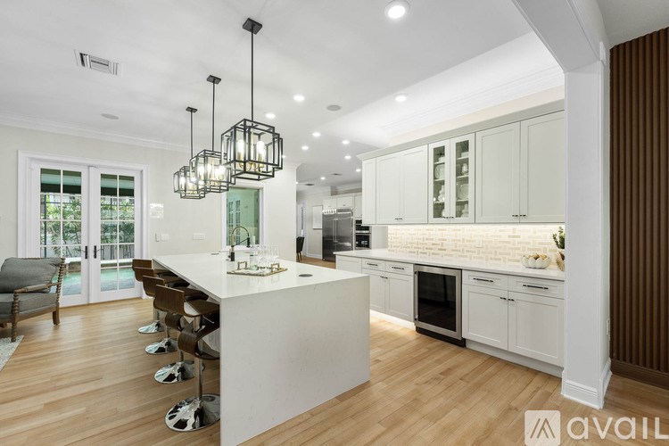 A modern kitchen with a white island and wooden floors.