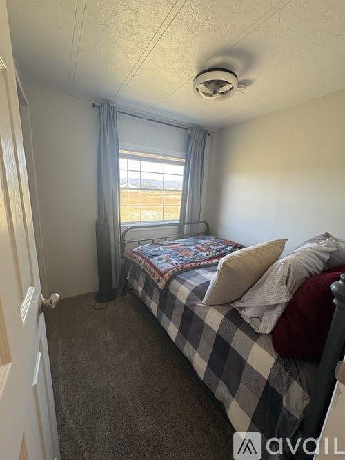 A bedroom with a bed and a window with curtains.