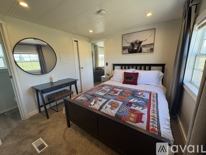 A bedroom with a bed, a table, and a framed picture on the wall.