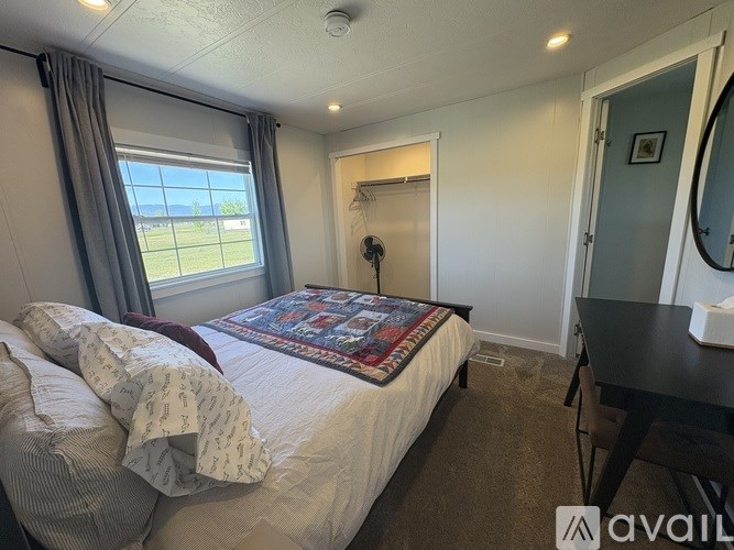 A bedroom with a bed, a window, and a small table.