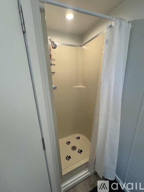 A bathroom with a shower curtain and a shower with paw prints on it.
