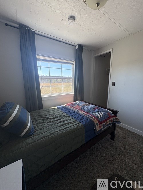 A bedroom with a bed, pillows, and a window with curtains.