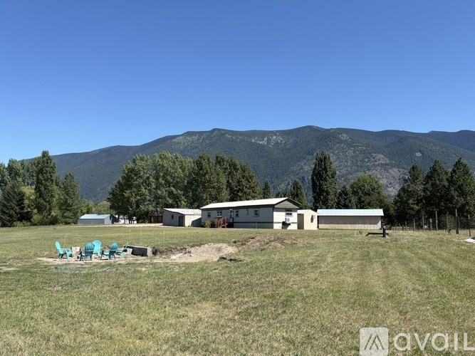A house is situated in a field with mountains in the background.