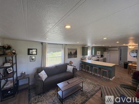 A living room with a grey couch and a bar area in the background.