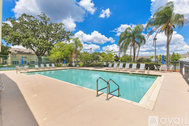 A large outdoor swimming pool surrounded by palm trees and lounge chairs.