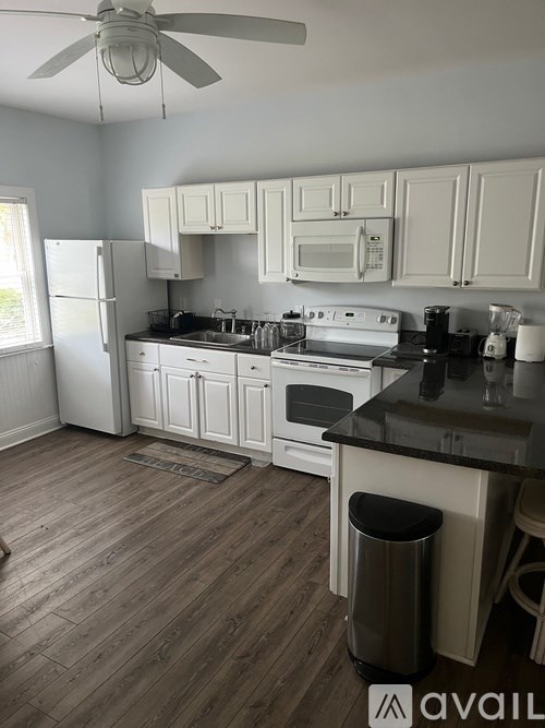 A kitchen with white cabinets and a black countertop.