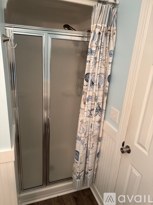 A bathroom with a glass shower door and a patterned shower curtain.