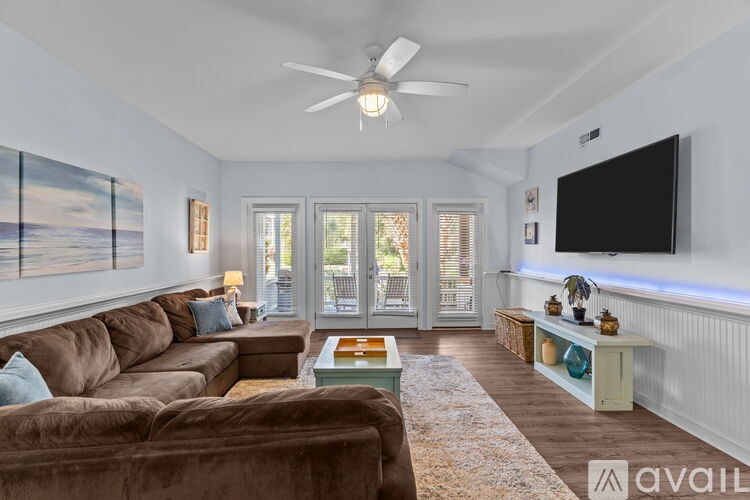 A patio with blue chairs and a table is surrounded by greenery.