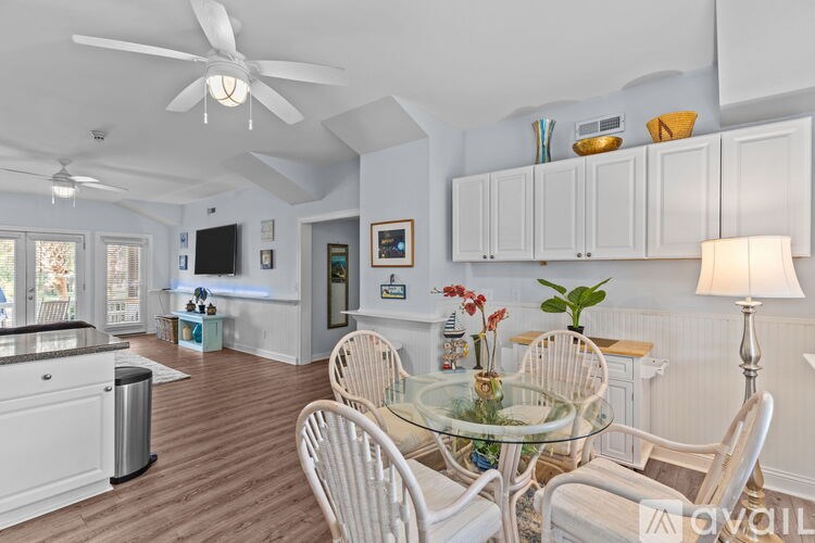 A living room with a glass table and white chairs.