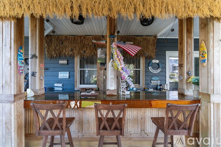 A bar with a thatched roof and wooden chairs.