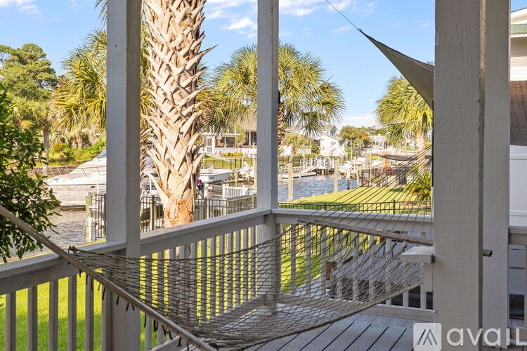 A balcony with a metal railing and a view of a palm tree and a body of water.