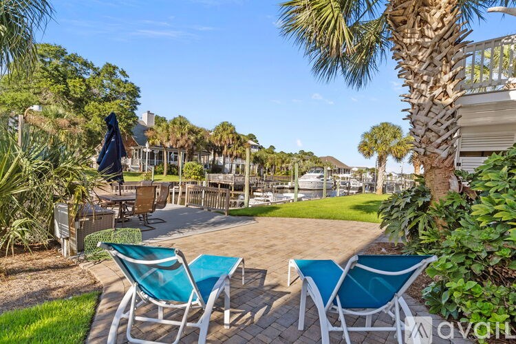 A patio with two chairs and a table is surrounded by greenery.