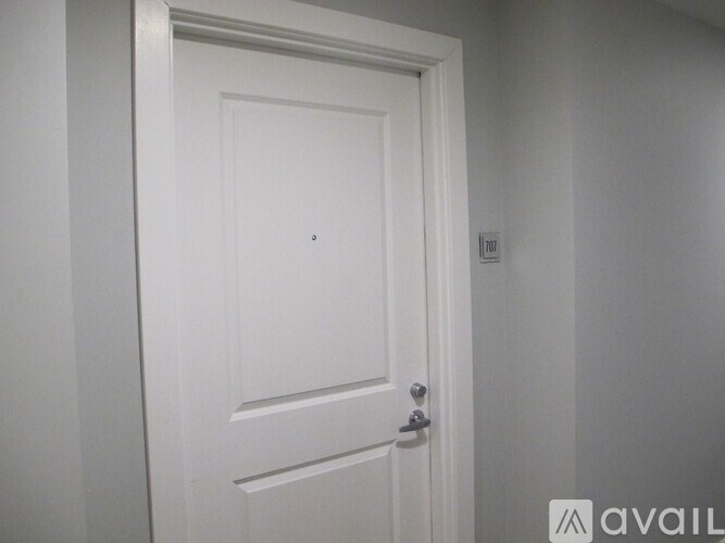 A white door with a silver handle is in a room with white walls.