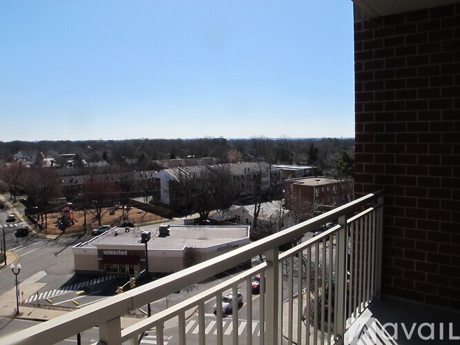 A view from a balcony overlooking a parking lot and buildings.