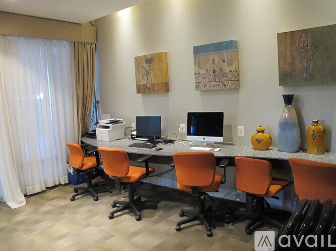 A room with a desk and chairs and two paintings on the wall.