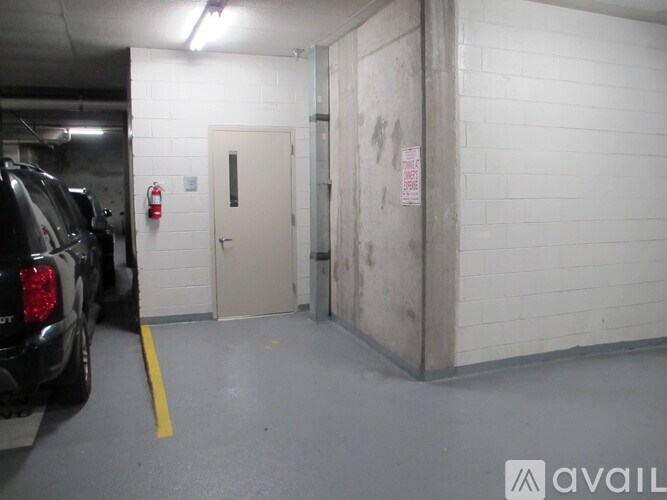 A parking garage with a black truck parked in the spot next to a white door.