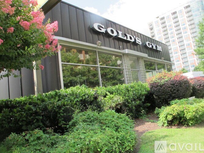 A gym named Gold's Gym is surrounded by greenery.