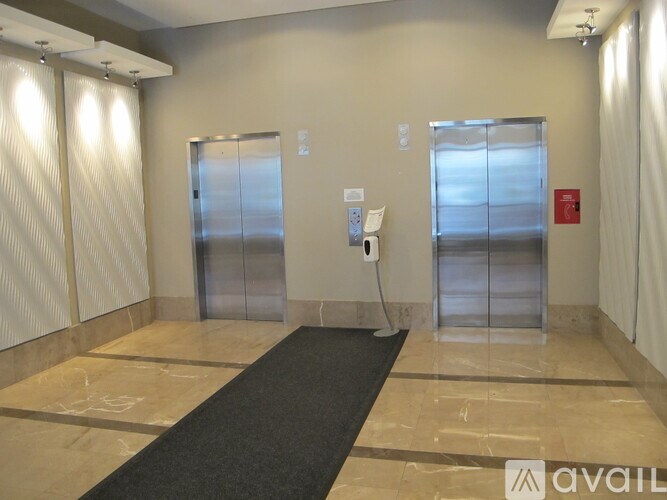 A hallway with a black carpet leading to a set of double doors.