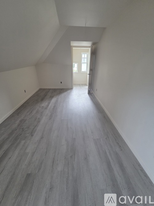 A hallway with wooden flooring and a white door at the end.