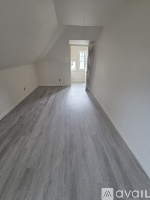 A hallway with wooden flooring and a white door at the end.