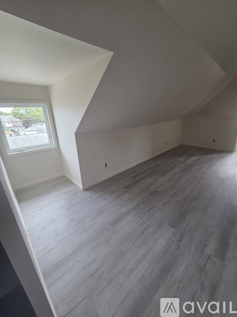 A room with wooden flooring and a window.