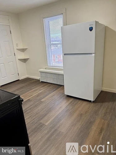 A kitchen with a black fridge and wooden floors.
