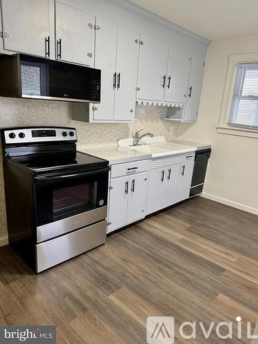 A kitchen with a black stove top oven and white cabinets.