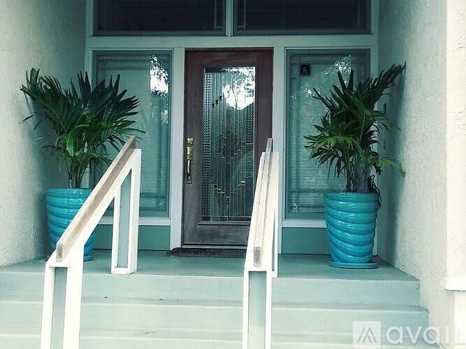 A white railing leads up to a brown door with a glass panel.