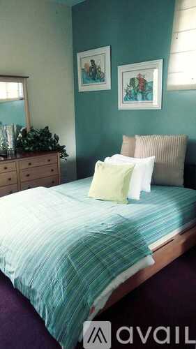 A bed with a green bedspread and pillows in a room.
