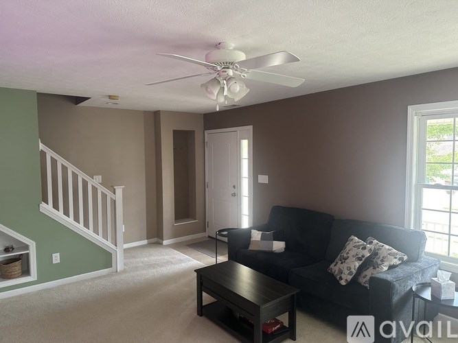 A living room with a couch, a coffee table, and a ceiling fan.