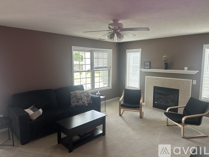 A living room with a black couch, a coffee table, and a fireplace.