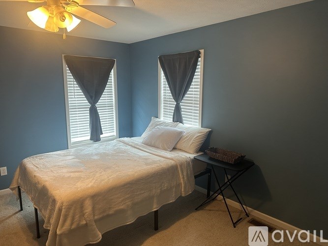 A bedroom with a bed, a small table, and a ceiling fan.
