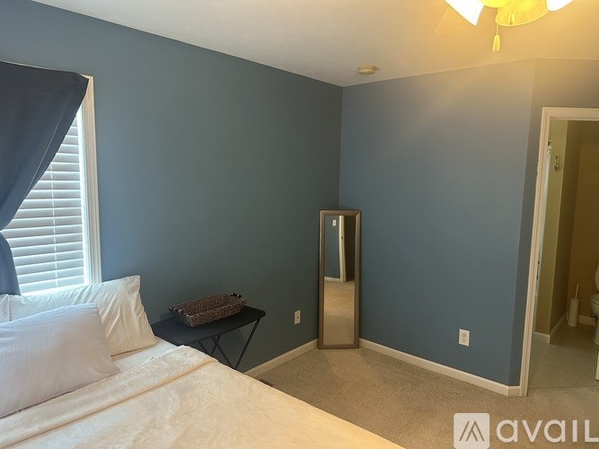 A bedroom with blue walls and a white bed.