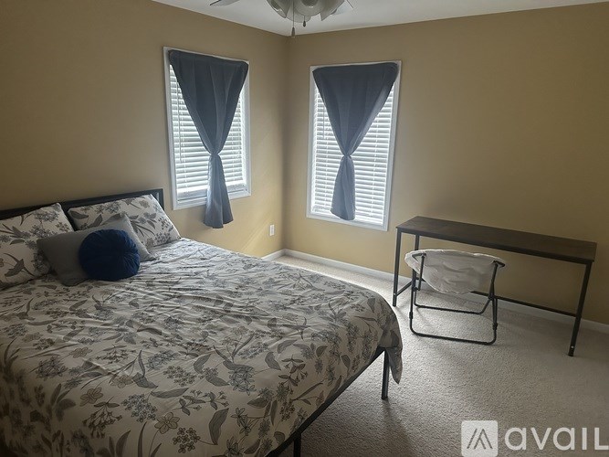 A bedroom with a bed, a chair, and a window with curtains.