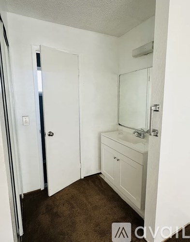 A bathroom with brown carpeting and white walls.