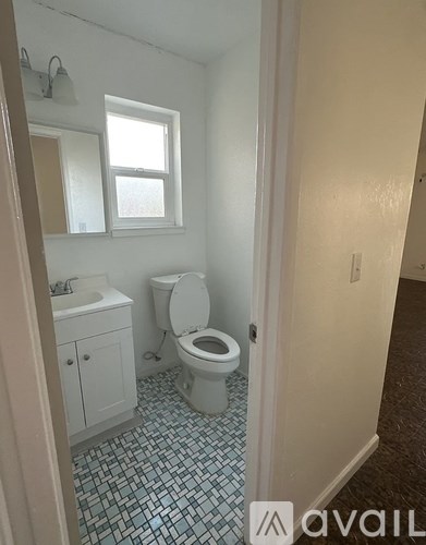 A bathroom with a toilet, sink, and a window.