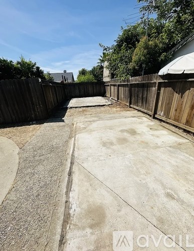 A backyard with a concrete patio and a wooden fence.