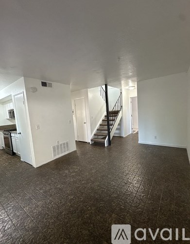 A spacious room with a staircase and a kitchen area.